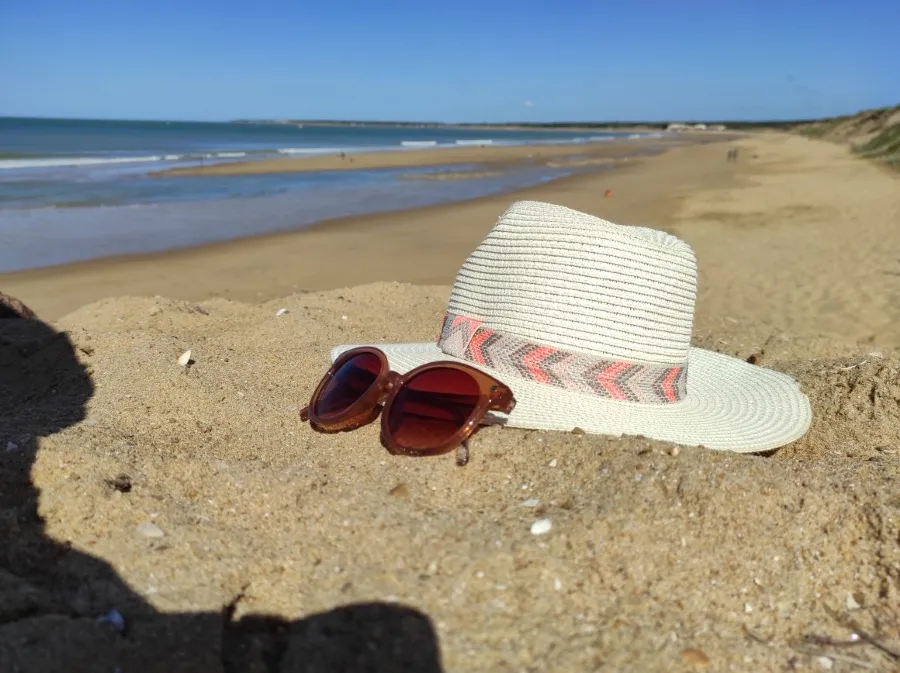 Détente sur le sable fin : chapeau et lunettes de soleil sur une plage de Longeville-sur-Mer.